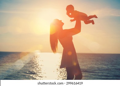 Mother And Baby Having Fun At Sunset On The Beach
