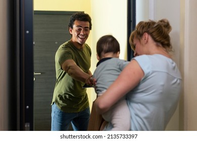 A Mother With A Baby In Her Arms At The Door Of Her Home Picks Up The Package Delivered By A Delivery Man.