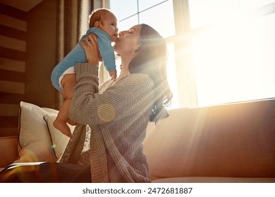 Mother, baby and kiss on cheek in living room on sofa with love for relationship with new born, care. Embrace, light and sunshine for relax on couch with playing, joy and happiness for wellness. - Powered by Shutterstock