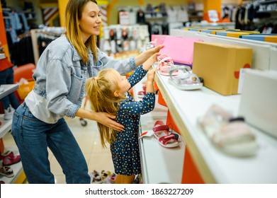 Mother and baby looking on shoes in kid's store