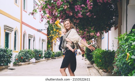 Mother And Baby On Beautiful Street Full Of Blooming Trees In Puerto Mogan Town, Gran Canaria, Spain. Active Travel Family Vacation In Canary Islands. Woman With Child Journey In Europe.