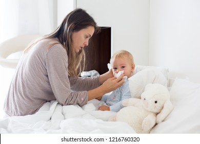 Mother And Baby In Pajamas, Early In The Morning, Mom Taking Care Of Her Sick Toddler Boy. Baby In Bed With Fever And Running Nose