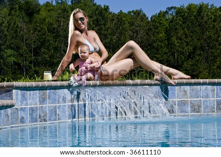Mother and baby playing by swimming pool