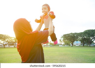 Mother And Baby Playing Together At Green Field With Warm Sunlight