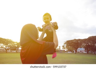 Mother And Baby Playing Together At Green Field With Warm Sunlight