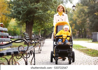 Mother With Baby In Pram Walking In Autumn Park