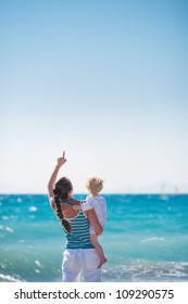 Mother And Baby At Sea Shore Pointing Up On Copy Space