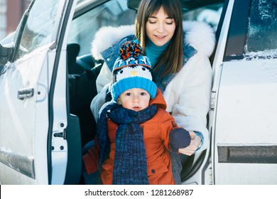 Mother And Baby Toddler Son In Warm Bright Winter Clothes Going Out From The Car Get Ready To Walk In A Winter Snowy Day. Happy Family. Childhood And Parenthood Happiness. Close Up