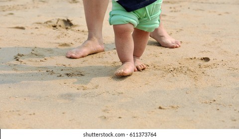 Mother And Baby Walking On Beach 