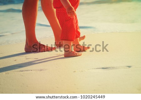 Mother and baby walking on sand beach