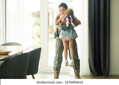 Mother Back Home. Woman Wearing Military Uniform Lifting Her Little Daughter While Coming Back Home