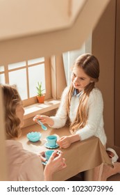 Mother And Beautiful Daughter Having Tea Party In Cardboard House