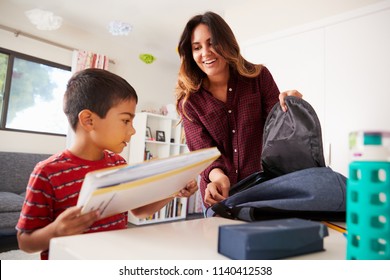 Mother In Bedroom Helping Son To Pack Bag Ready For School