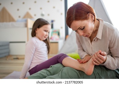 Mother Blowing Her Little Daughter's Hurt Ankle.