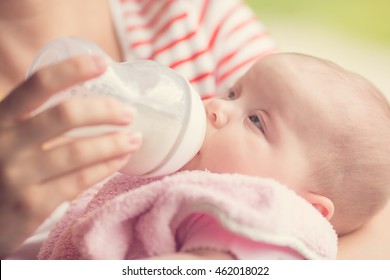 Mother Bottle Feeding Her Newborn Baby Girl In The Park; Instagram Style Filter Applied In Post Processing