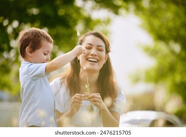 Mother, boy and flowers in nature to play together, love and bonding in outdoor for learning plants. Mommy, son and happiness in field or laughing for comedy, peace and funny childhood on vacation - Powered by Shutterstock