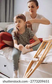Mother braiding her physically disabled daughter's hair, sharing a caring moment. Crutches visible near the bed