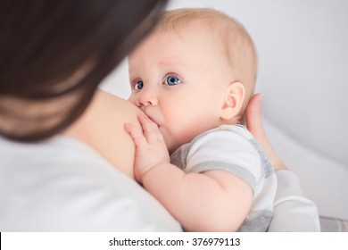 mother breast feeding and hugging her baby