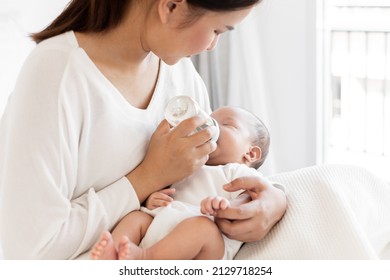 Mother Breast Feeding Milk To Asian Newborn Baby On White Bed