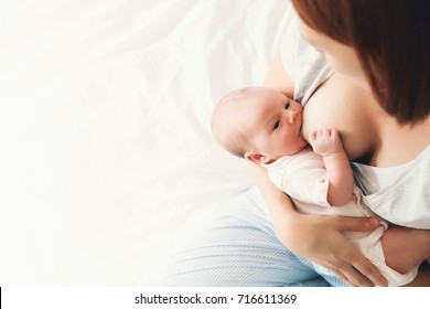 Mother breastfeeding baby in her arms at home. Beautiful mom breast feeding her newborn child. Baby eating mother's milk. Young woman nursing and feeding baby. Concept of lactation infant.