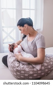 mother breastfeeding baby on support cushion 