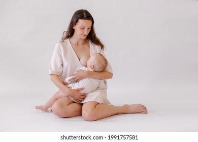 mother is breastfeeding her baby. Woman in white and child on her arms. Kid sucks breast milk. Holy motherhood. Caring tenderness protection. Mother love concept.  Natural nutrition. Eco parenting