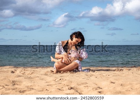 Mother breastfeeding her daughter on the shore of the beach