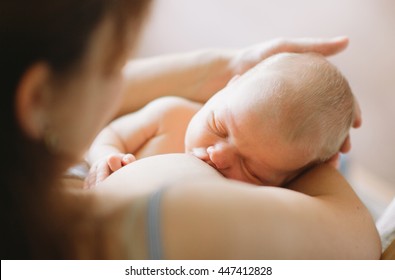 Mother breastfeeding her newborn child. Mom nursing and feeding baby. Close-up portrait.