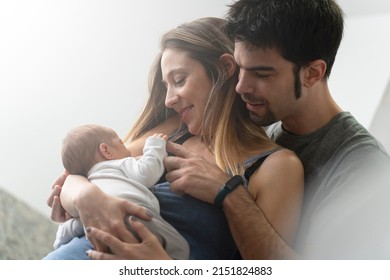 Mother breastfeeding her son in the kitchen with his father by her side