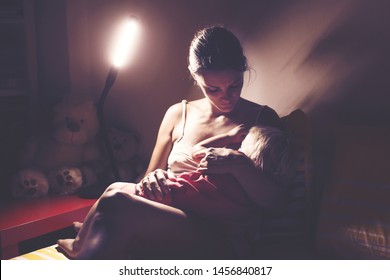 Mother, Breastfeeding Her Toddler Boy At Home At Night, Night Stand Lamp Turned On, Mom And Baby Hugging