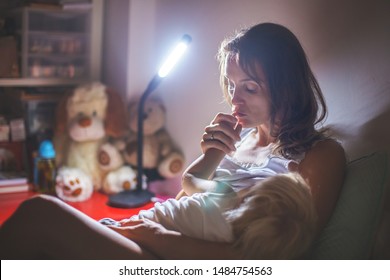 Mother, Breastfeeding Her Toddler Boy At Home At Night, Night Stand Lamp Turned On, Mom And Baby Hugging