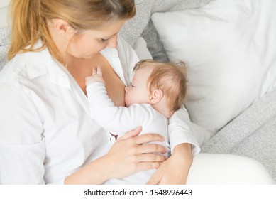mother breastfeeding and hugging baby.