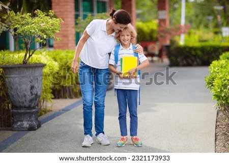 Mother bringing child to school. Parents pick up little boy after class. Young mom picking up kid after lessons in kindergarten or preschool. First day of school year. Kids happy to be back to school.