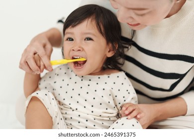 mother brushing her little daughters teeth. happy baby with tooth brush - Powered by Shutterstock