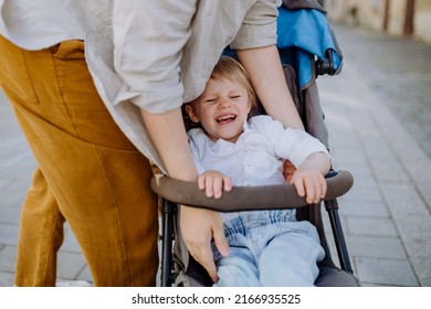 Mother calming a crying child sitting in a stroller while walking down the street