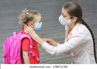 A mother carefully adjusts her little daughter's medical mask. Concept of education and training - Powered by Shutterstock