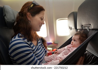 Mother Carry Her Infant Baby During Flight.Concept Photo Of Air Travel With Baby. Real People. Copy Space