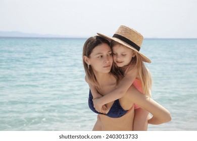 Mother carrying daughter on the beach. Happy idyllic family summer vacation concept.	 - Powered by Shutterstock