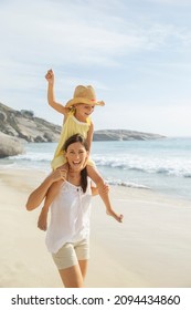 Mother Carrying Daughter On Shoulders On Beach