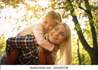 Mother carrying her daughter on piggyback. - Shutterstock ID 1052645738
