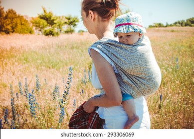 Mother Carrying Her Little Child In A Baby Sling