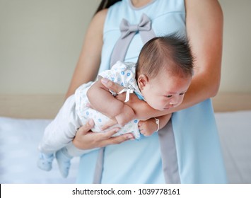 Mother Carrying Upside Down Infant Baby For Decrease Baby Stomach Pain. Baby Health Care Concept