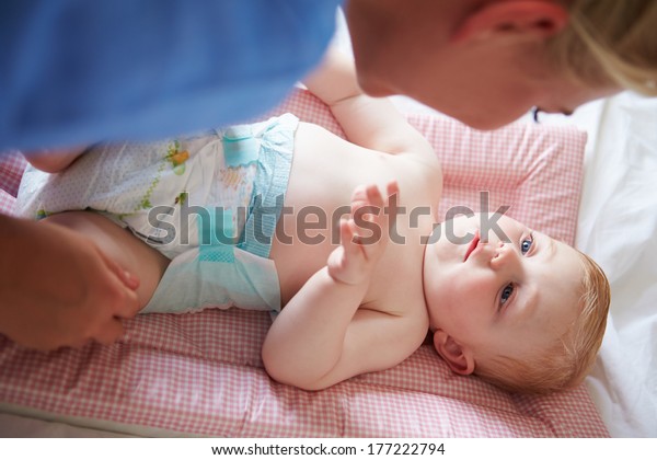 Mother\
Changing Baby Son\'s Nappy As He Lies On\
Mat