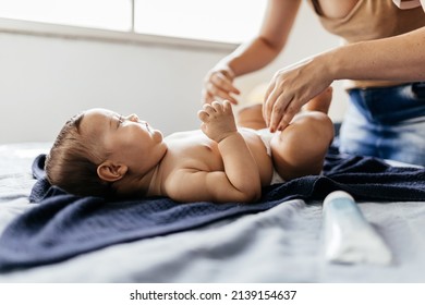 Mother Changing Baby's Diaper In Bed. Mother Applies Diaper Rash Cream.
