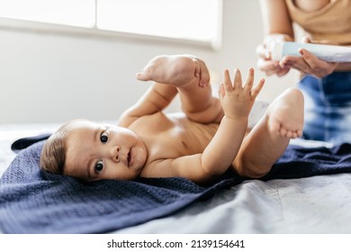 Mother Changing Baby's Diaper In Bed. Mother Applies Diaper Rash Cream.