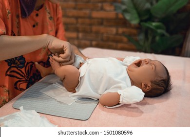 Mother Changing Diaper Of His Newborn Baby Daughter At Home