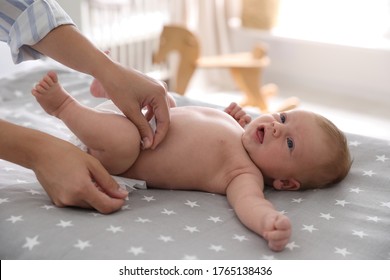 Mother changing her baby's diaper on bed - Powered by Shutterstock