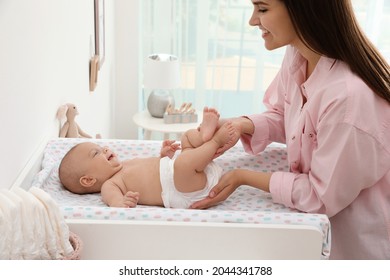 Mother changing her baby's diaper on table at home - Powered by Shutterstock