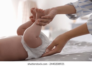 Mother changing her baby's diaper on bed, closeup
