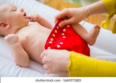 Mother changing reusable diaper or nappy. Reusable diaper and infant. Baby with eco diaper.  - Shutterstock ID 1669371883